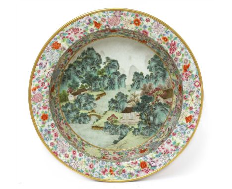 A Chinese famille rose basin, of deep circular form with flat everted rim, the well painted with pavilions in a mountainous l