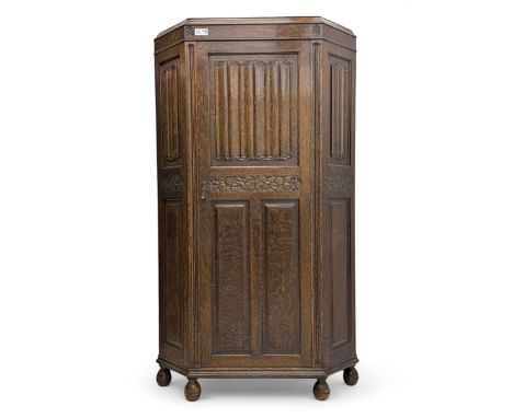 Early 20th century oak corner hall wardrobe, moulded top above a carved floral frieze, single door with linenfold panels and 