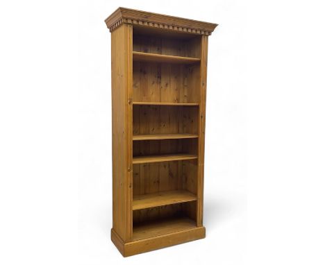 Georgian design pine open bookcase, projecting dentil cornice over five adjustable shelves, flanked by fluted pilasters, on p