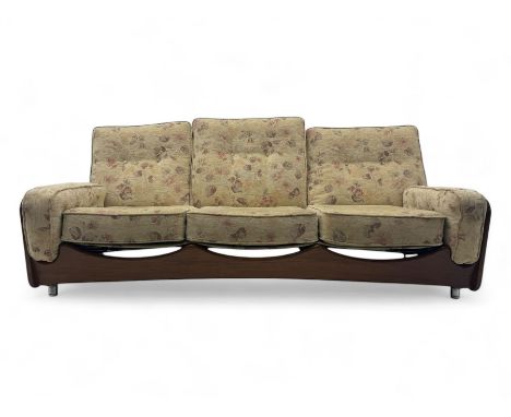 Mid-20th century three-seat sofa with floral patterned upholstery, supported by a sculpted teakwood frame with curved cutout 