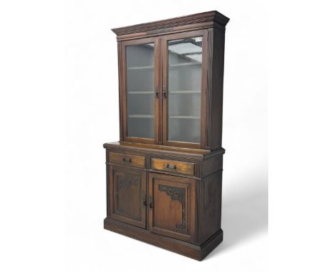 Edwardian walnut bookcase on cupboard, projecting moulded cornice over two glazed doors enclosing three shelves, lower sectio