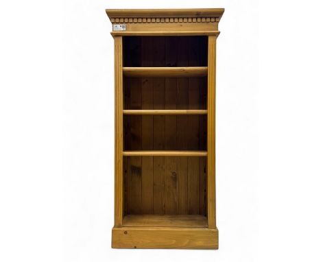 Contemporary pine bookcase, projecting moulded cornice with dentil frieze over three adjustable shelves, flanked by fluted up