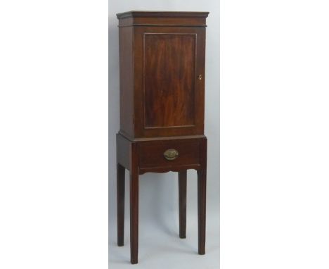 A mahogany cabinet on stand, the oblong cabinet with slightly flared cornice over single panelled door enclosing a shelf on b