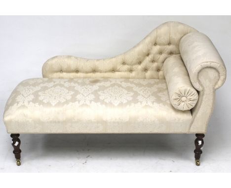 A small chaise lounge. Upholstered in cream patterned fabric with a button back, raised on turned supports with casters, H74c