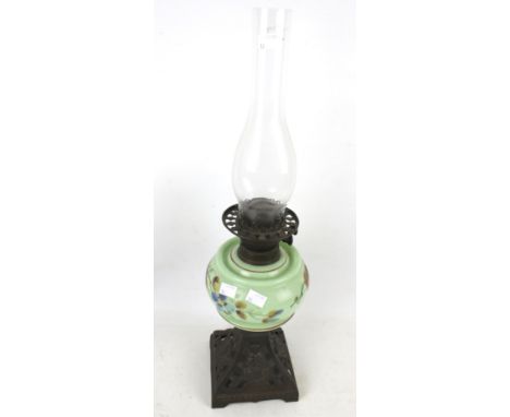 A Victorian oil lamp. Having an opaque green glass reservoir painted with flowers, mounted on a square cast metal base, H60cm