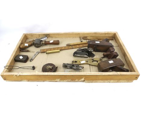 An assortment of vintage hand tools. Including a leather bound tape measure, planes, three rulers, etc.