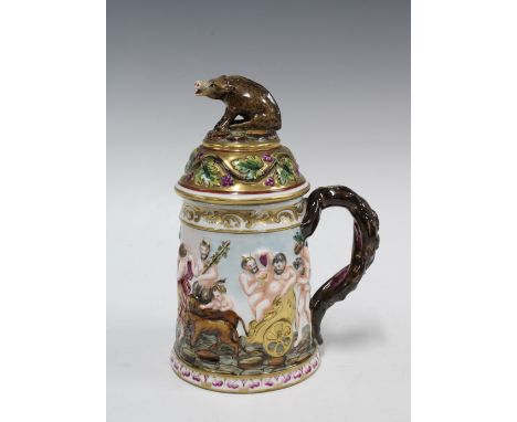 A Capo di Monte tankard decorated in relief with bacchanalian figures, the cover with a boar finial, 22cm, (a/f, repair to ba