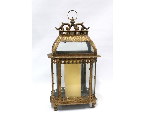 Gilt metal and glass panelled storm lantern with a church candle, 55cm 