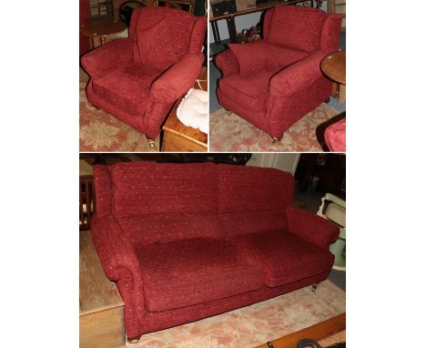 A Park Knoll three-piece suite comprising two chairs and a three-seater sofa, each upholstered in red fabric and with scroll 