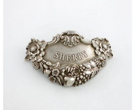 A George III silver wine label, by Paul Storr, London 1818, shaped form, heavily decorated with flowers, vines and shell deco