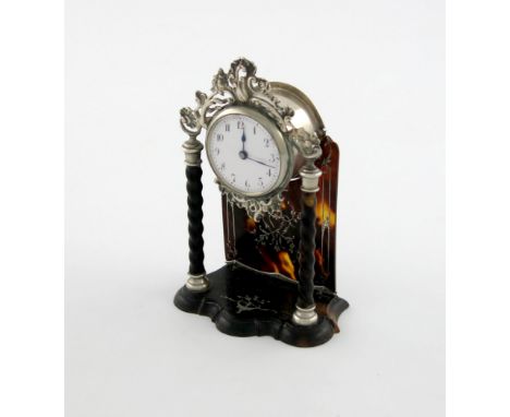 λ A silver-mounted tortoiseshell clock, by William Comyns, London 1912, circular form, with a pierced foliate scroll pediment