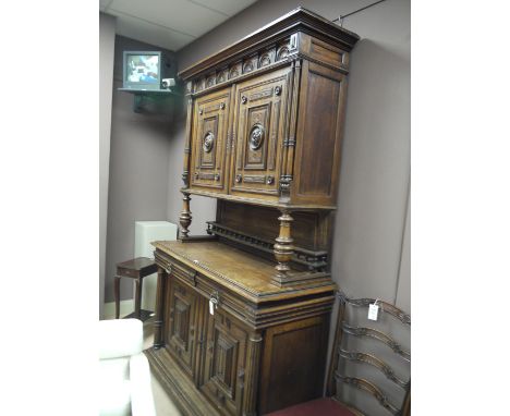 A large heavily carved and stained oak dresser with flared cornice and heavily carved frieze, the cupboard with two carved pa