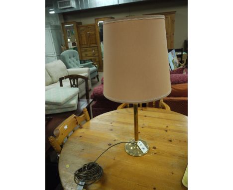 A brass table lamp with tapering pale terracotta shade.