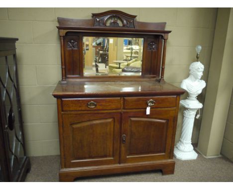 A 19th Century Arts & Crafts style carved and stained oak sideboard, the back panel with rectangular bevelled mirror flanked 