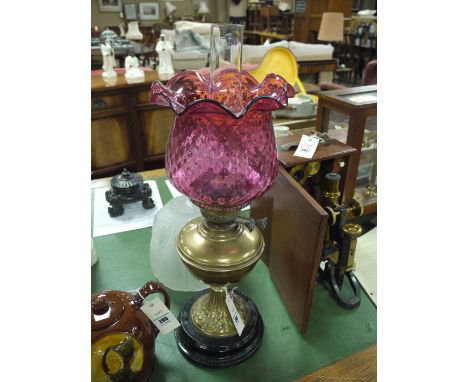 A Victorian brass table lamp with cranberry shade; and another plain glass shade.