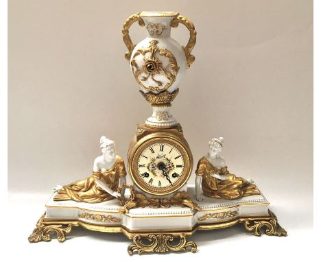 A Continental porcelain and gilt metal mantel clock, Gilt metal drum movement flanked by reclining gilt robed maidens, with u