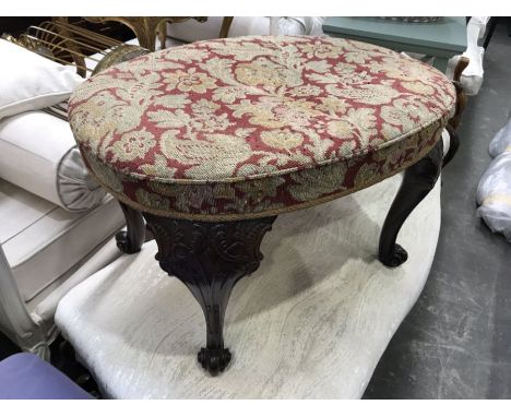A George II style mahogany and tapestry upholstered stool, oval form, with foliate carved cabriole  on carved scroll feet, 45