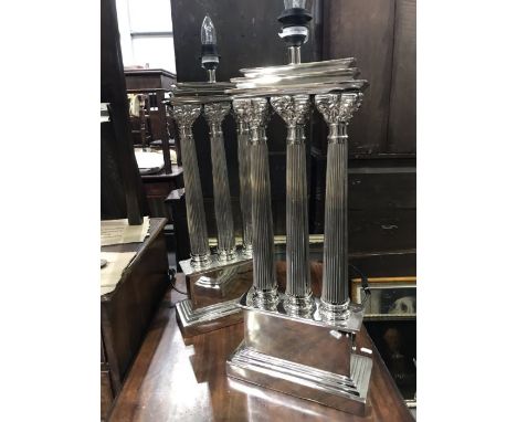 Two pairs of gilt and silvered metal table lamps including a pair of architectural table lamps, each modelled as three Corint