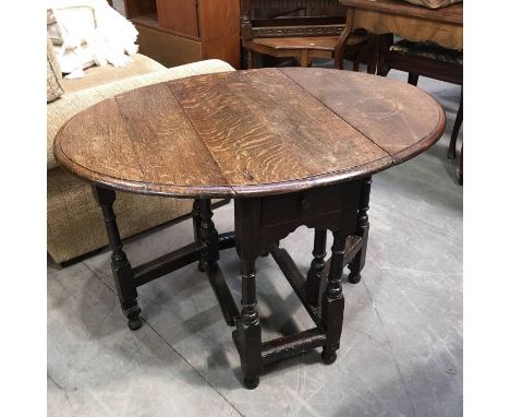 An antique oak gate leg table, pegged oval top above single frieze drawer,  on ring turned and block supports, 105cm wide