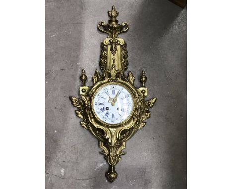 A gilt metal Lava wall clock, in the French 1880's style surmounted by a flaming urn finial, 63cm long