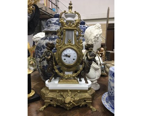 An Imperial Italian gilt metal mantel clock, lyre form flanked by cherubs, on white marble base and cast base, raised on lion