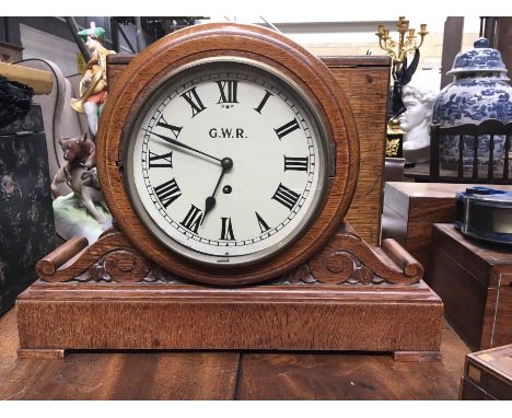 A GWR oak cased clock painted circular dial flanked by foliage scrolls on plinth base 35cm high, 46cm wide