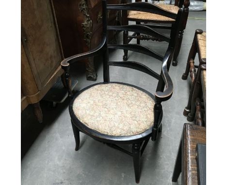 An ebonised aesthetic armchair, carved ladder back, curved Inswept arms, oval padded seat on turned supports and stretchers 