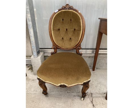 A VICTORIAN WALNUT NURSING CHAIR ON FRONT CABRIOLE LEGS, HAVING CARVED KNEES, OVAL BUTTON-BACK WITH CARVED TOP RAIL 