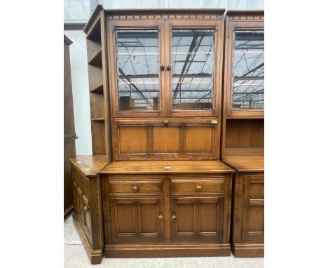 AN ERCOL ELM GOLDEN DAWN DRESSER/COCKTAIL CABINET WITH CUPBOARDS AND DRAWERS TO THE BASE, GLAZED UPPER PORTION WITH PULL-DOWN