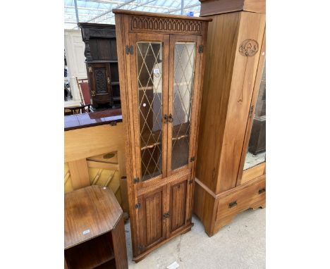 AN OAK OLD CHARM STYLE TWO DOOR GLAZED CORNER CABINET WITH TWO LINENFOLD DOORS TO BASE, 26" WIDE 