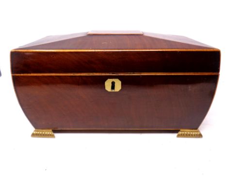 A good quality Regency mahogany sarcophagus tea caddy on raised brass feet containing a Chinese blue and white ceramic bowl (