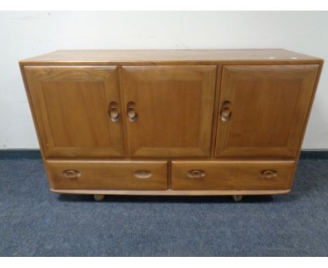 An Ercol elm and beech three door, two drawer sideboard on casters (as found) CONDITION REPORT: Damages to handles. 