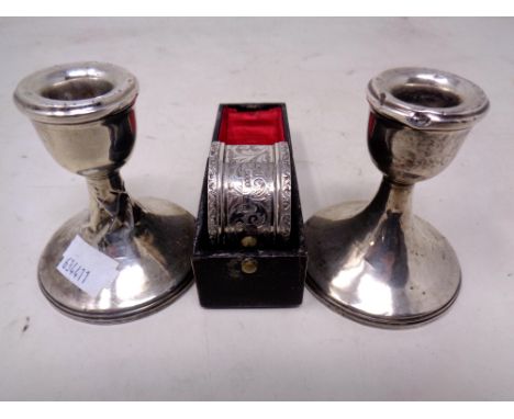 A pair of silver squat candlesticks (height 7cm, weighted) with a further silver napkin ring in case.