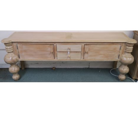 A modern limed pine console table with two drawers flanked by two doors with baluster shaped supports, retailed by Design Wor