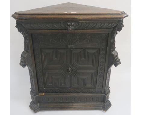 A Continental oak corner cabinet with single carved frieze drawer with mask handle over a carved panel door and carved suppor