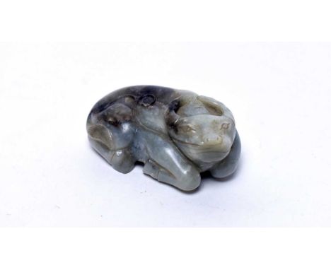 A Chinese green jade pebble carving of a recumbent water buffalo, Qing, with black and white marbled inclusions, 7.5cms.