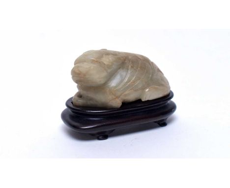 A Chinese pale green jade pebble carving of a recumbent water buffalo, Qing, with rust inclusions, on fitted hardwood stand, 