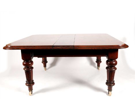 A Victorian mahogany extending dining table, the bevelled rectangular top with rounded corners and three extra leaves, key wo