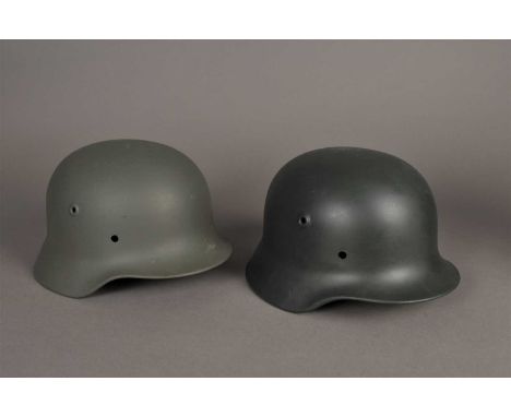 Two German WWII steel helmet shells - re-painted light and dark green, the lighter example stamped M65 and 064; the darker ex