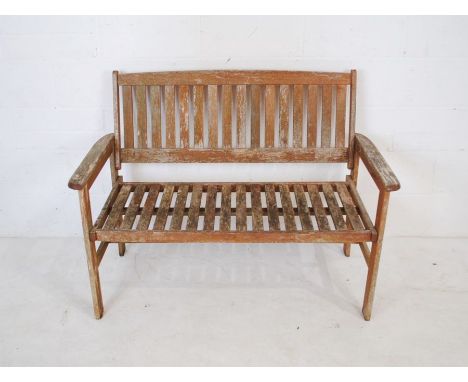 A weathered wooden garden bench with slatted seat - length 120cm