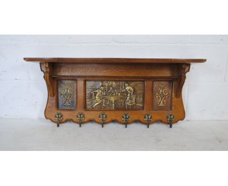 A turn of the century oak hall shelf with ornate brass panelling and six coat hooks - length 93cm