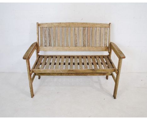 A weathered wooden garden bench with slatted seat - length 120cm