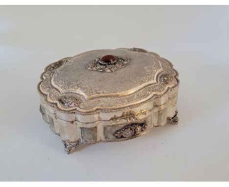 A baroque silver box,&nbsp;having lobed side with textured panels and applied floral decoration, the stepped lid similarly te