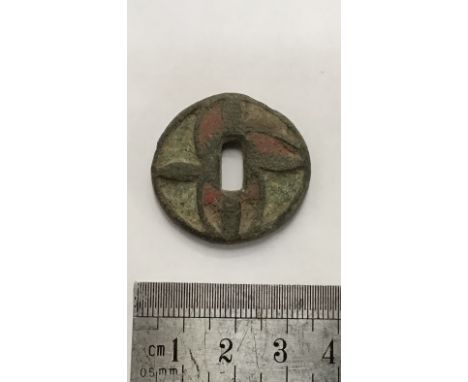                         Enamelled dagger mount. Copper alloy disc featuring an asymmetrical curvilinear design of red/white c