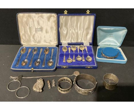 A set of six silver teaspoons, cased; another set of six silver teaspoons; a silver hinged bangle, another; silver napkin rin