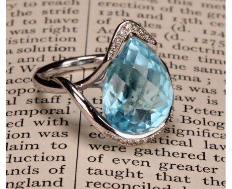 An impressive topaz and 18ct white gold ring, the large sky blue pear shape facet cut stone set within two bands of diamond c