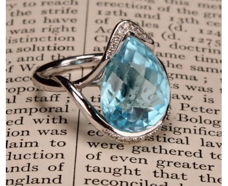 An impressive topaz and 18ct white gold ring, the large sky blue pear shape facet cut stone set within two bands of diamond c