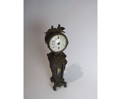 A late 19th Century mantel timepiece, with drum-shaped case raised upon an Art Nouveau bronze pillar set with an enamelled pl