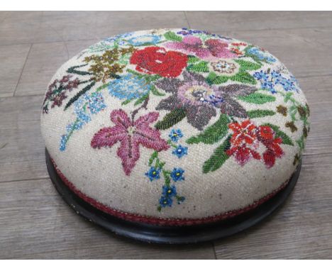 A bugle bead foot stool, the detail as a still life of flowers, 36cm diameter