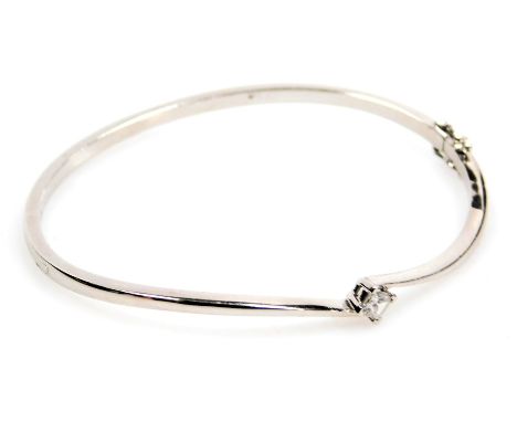 An 18ct white gold and diamond bangle, in a crossover design, set with a princess cut diamond, approx ¼ct, 15.6g.